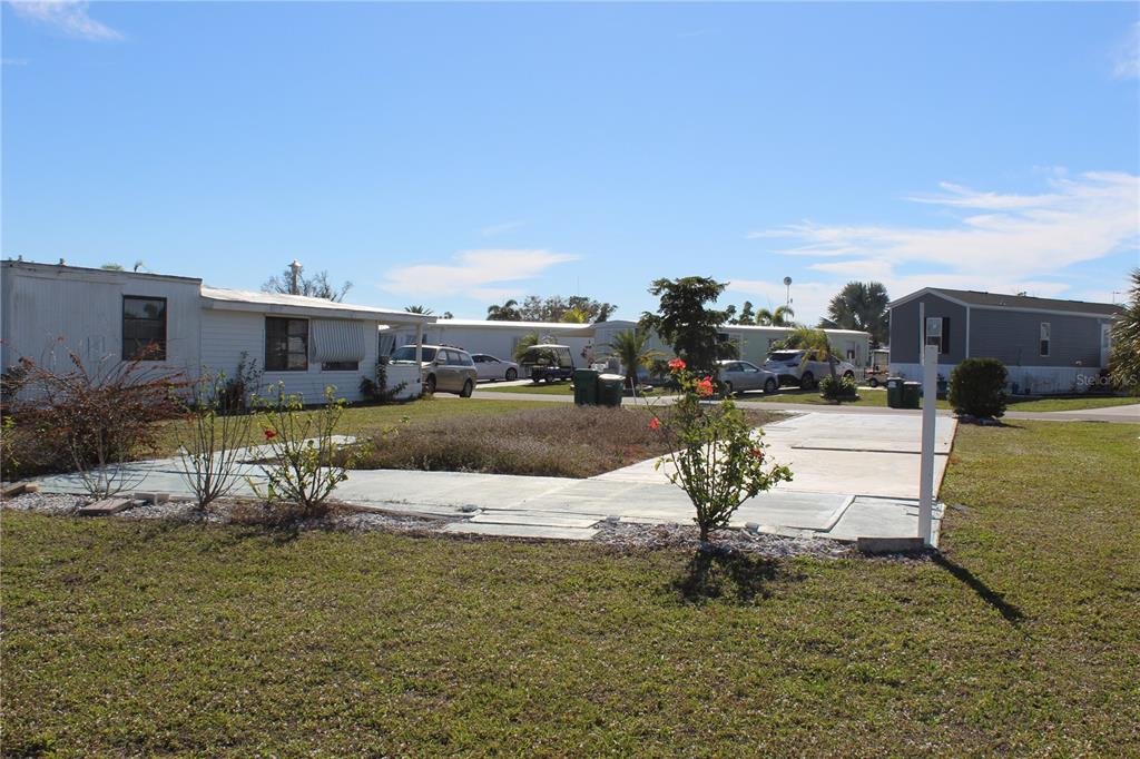 A vacant concrete pad sits in front of a white mobile home in a park — 7392 HESTON STREET, PORT CHARLOTTE, FL