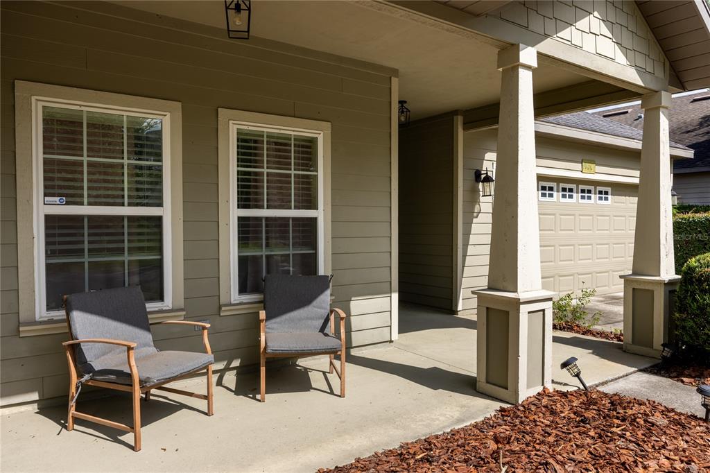 A tan house exterior features a covered front porch, a garage, and a concrete driveway — 7550 SW 81ST WAY, GAINESVILLE, FL