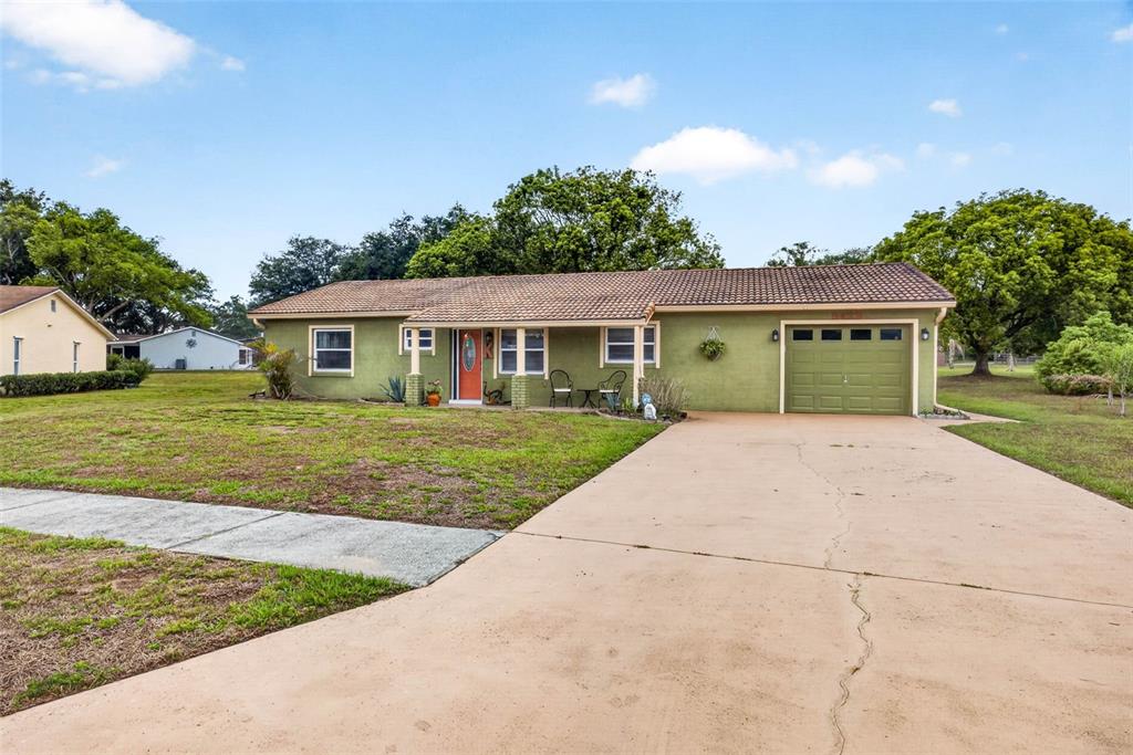 A single-story house with a green exterior, a tiled roof, and an attached garage — 8429 JACQUELINE COURT, ZEPHYRHILLS, FL