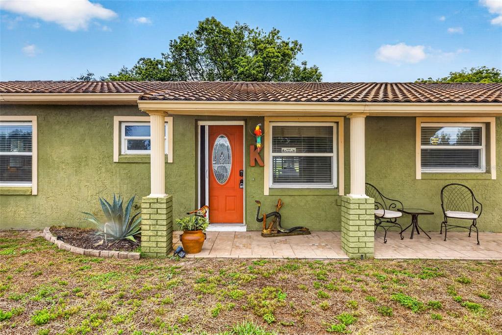 A single-story house with a green stucco exterior, a tiled roof, and a front porch — 8429 JACQUELINE COURT, ZEPHYRHILLS, FL