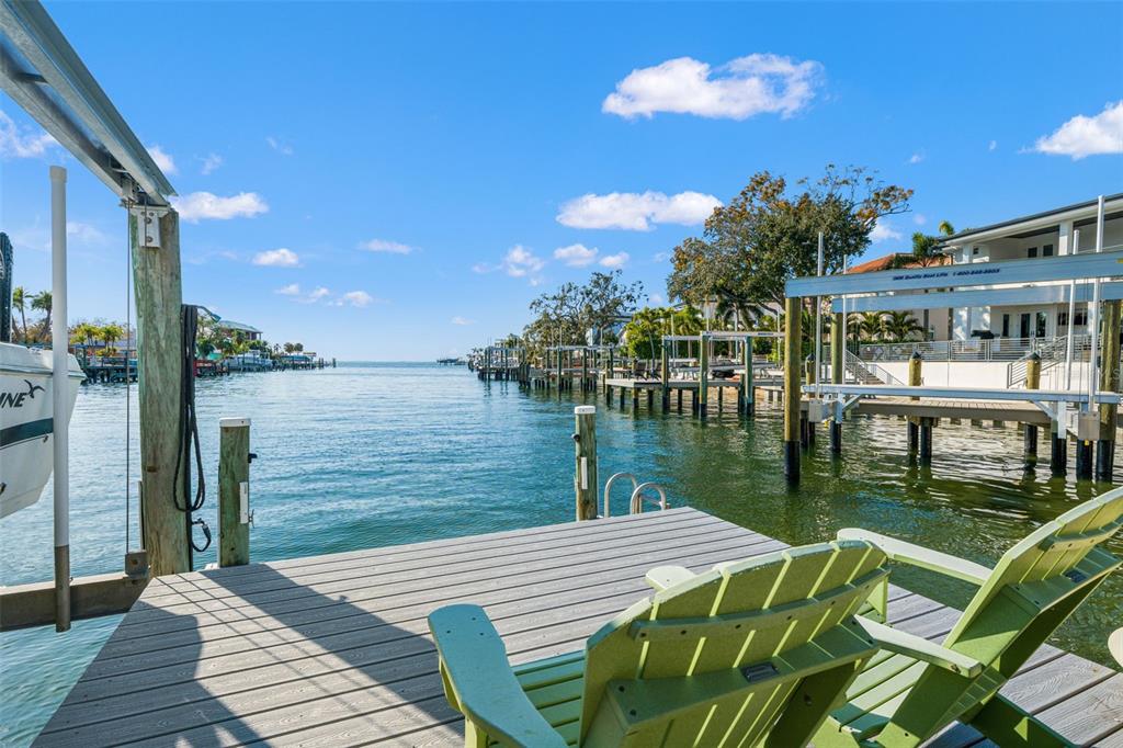 A wooden dock with two green chairs overlooks a canal leading to open water — 2605 S BEACH DRIVE, TAMPA, FL