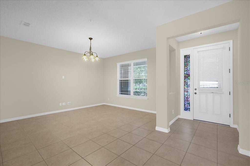 A dining room with beige walls, tile flooring, a chandelier, and a front entryway door — 8943 HILDRETH AVENUE, ORLANDO, FL