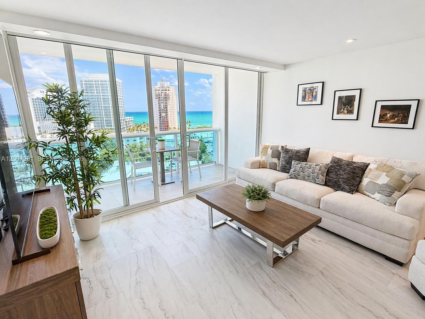 A living room with marble floors, a beige sofa, and a balcony overlooking the ocean — 6770 Indian Creek Dr # 12T, Miami Beach FL 33141, MIAMI BEACH, FL