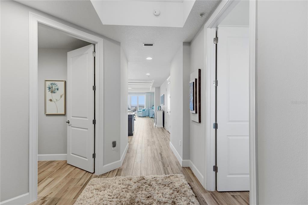 A hallway with light wood-look tile flooring leads toward an open living area — 807 S ATLANTIC AVENUE UNIT 303, NEW SMYRNA BEACH, FL