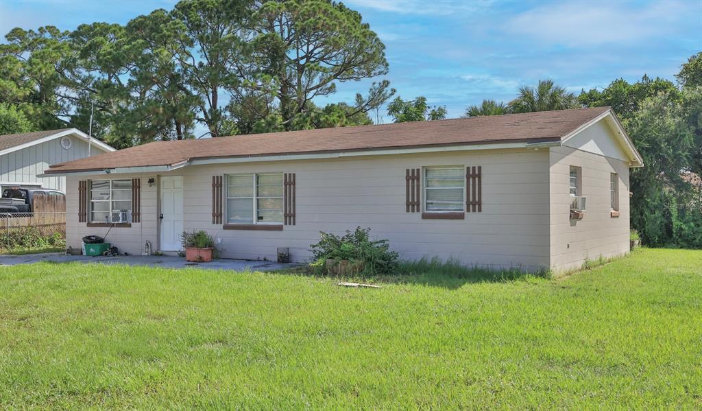 A single-story house with beige siding, a brown roof, and a large front lawn — 1863 FERN PALM DRIVE, EDGEWATER, FL