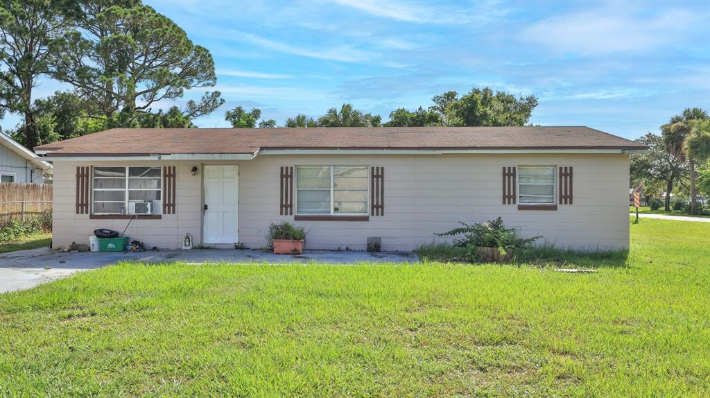 A single-story house with beige siding, a brown roof, and a front lawn — 1863 FERN PALM DRIVE, EDGEWATER, FL