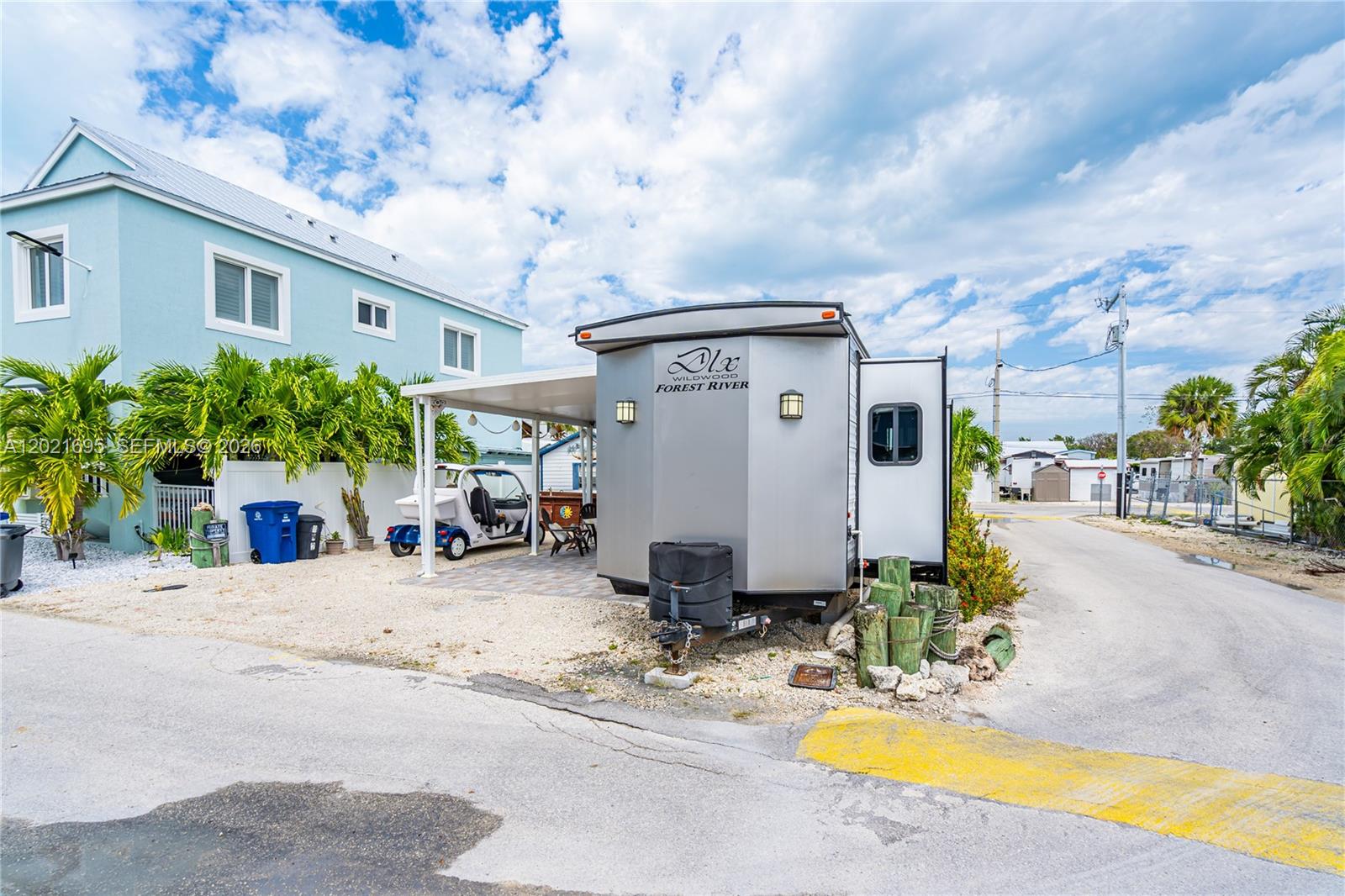 A Forest River Wildwood travel trailer is parked next to a light blue house — 325 Calusa St #252, Key Largo FL 33037, KEY LARGO, FL