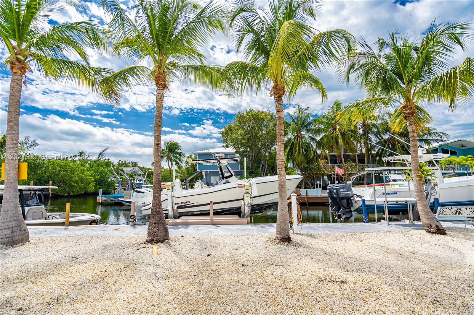 Three boats are docked in a canal lined with palm trees and gravel ground — 325 Calusa St #252, Key Largo FL 33037, KEY LARGO, FL