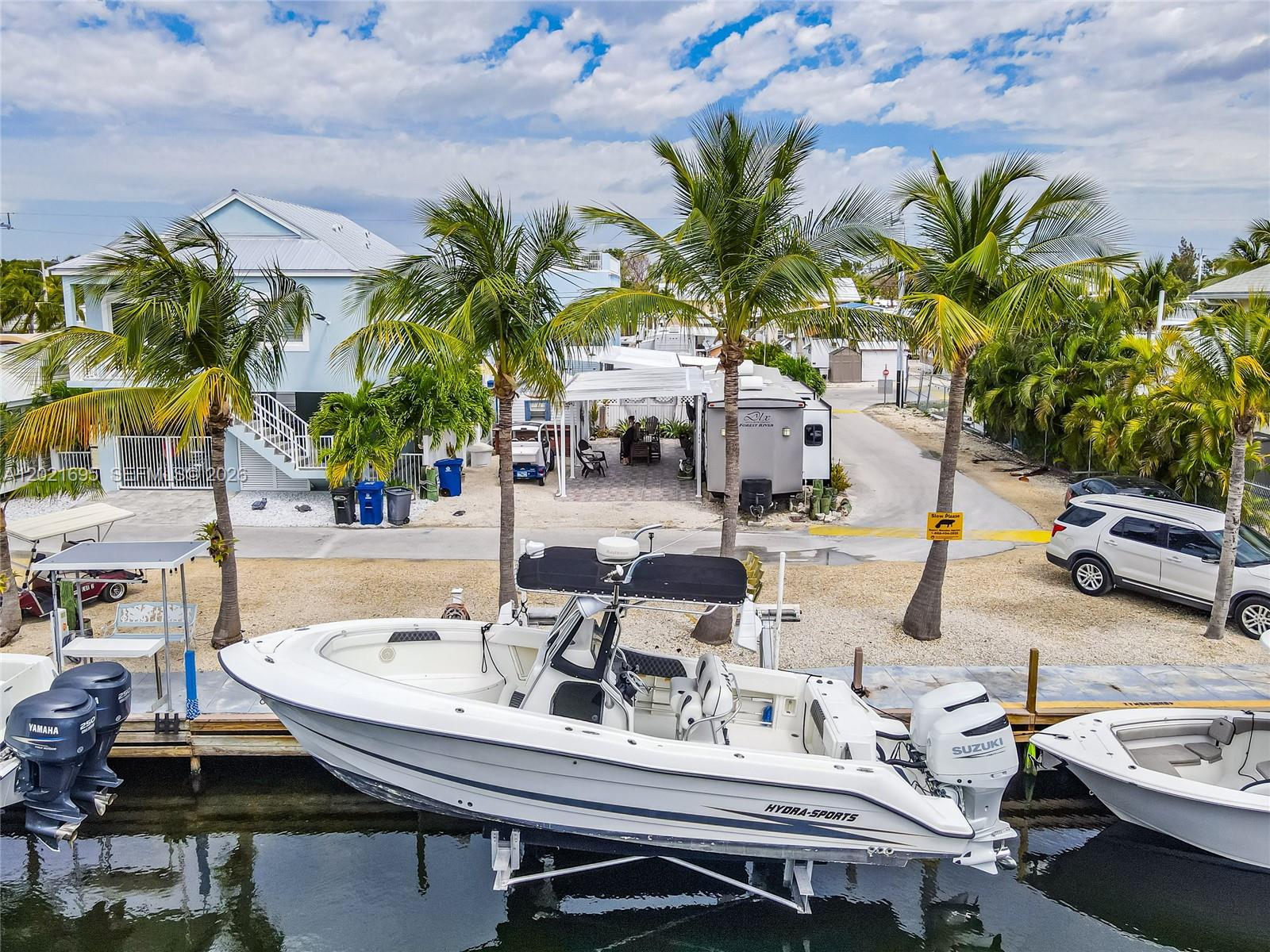 A white Hydra-Sports boat is docked in a canal next to a residential property — 325 Calusa St #252, Key Largo FL 33037, KEY LARGO, FL