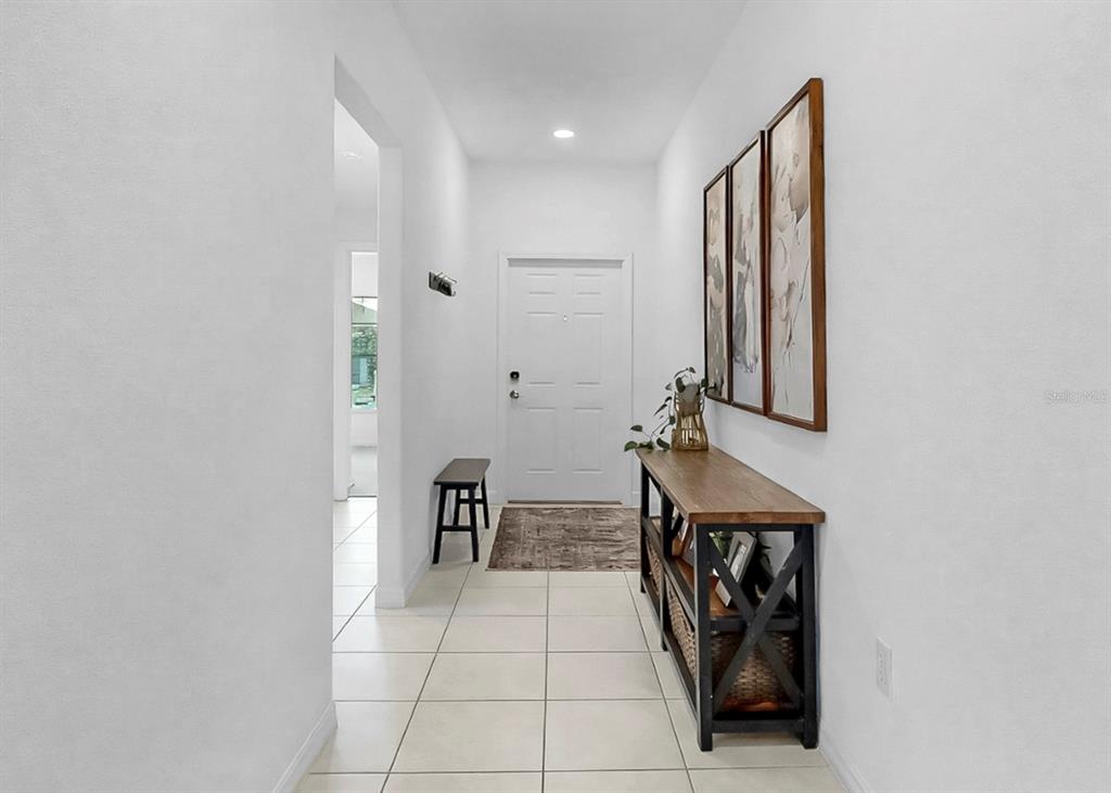 A bright entryway features white walls, tile flooring, a console table, and a front door — 13256 GREAT PLAINS DRIVE, RIVERVIEW, FL