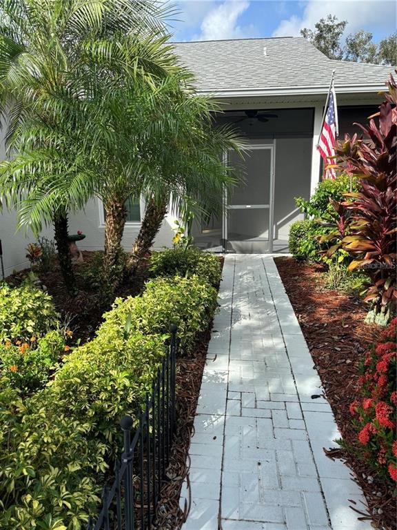 A paved walkway leads to the screened front entrance of a house with landscaping — 284 LAKE CASSIDY DRIVE, POINCIANA, FL