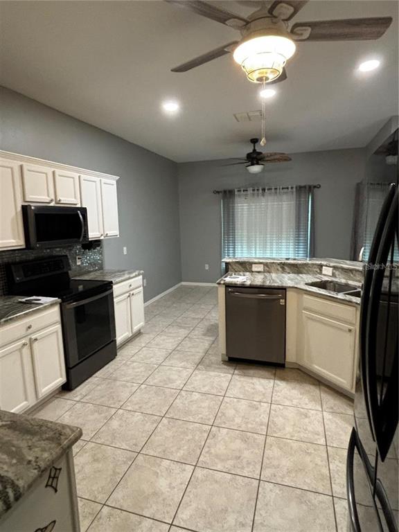 A kitchen features white cabinets, granite countertops, tile flooring, and two ceiling fans — 284 LAKE CASSIDY DRIVE, POINCIANA, FL