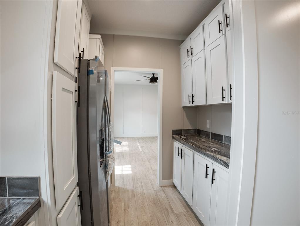 A kitchen features white cabinets, a stainless steel refrigerator, and dark countertops — 45 KELLY RIDGE ROAD, FROSTPROOF, FL