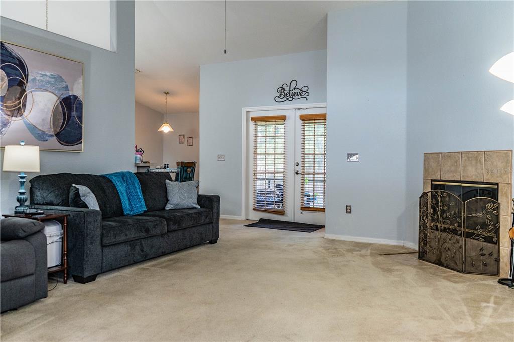 A living room features a dark sofa, a fireplace with a screen, and glass doors — 8010 ASHLEY POINTE DRIVE, LAKELAND, FL