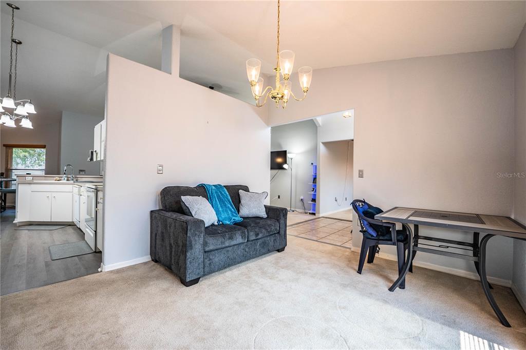 A living room with carpeted flooring, a dark sofa, and a dining table — 8010 ASHLEY POINTE DRIVE, LAKELAND, FL