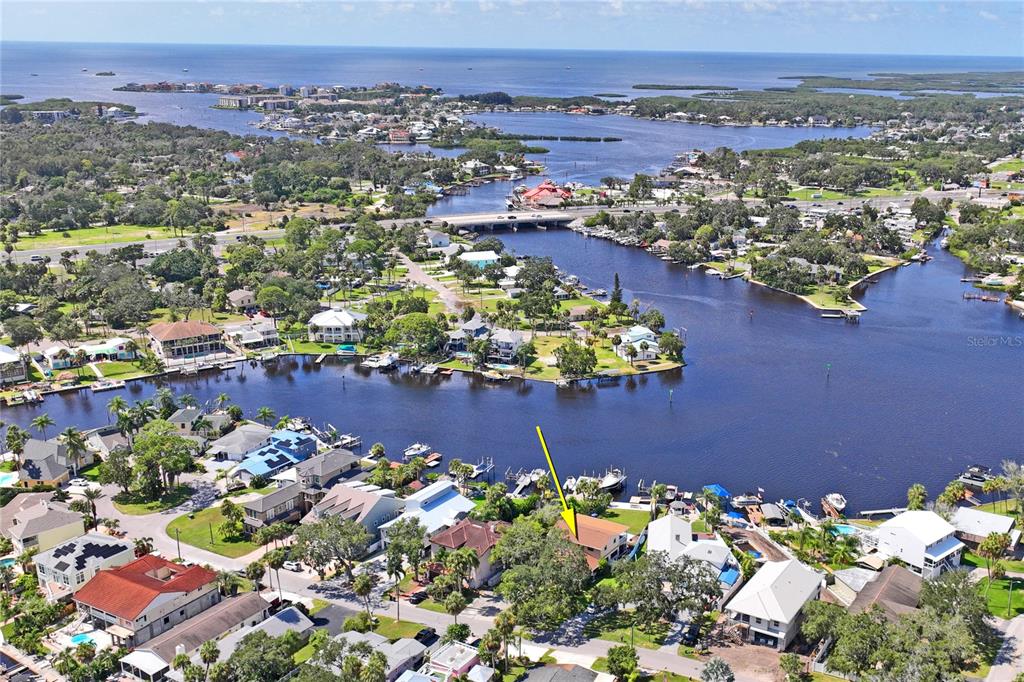 An aerial view shows a waterfront residential neighborhood with a yellow arrow pointing to a house — 5531 MANATEE POINT DRIVE, NEW PORT RICHEY, FL