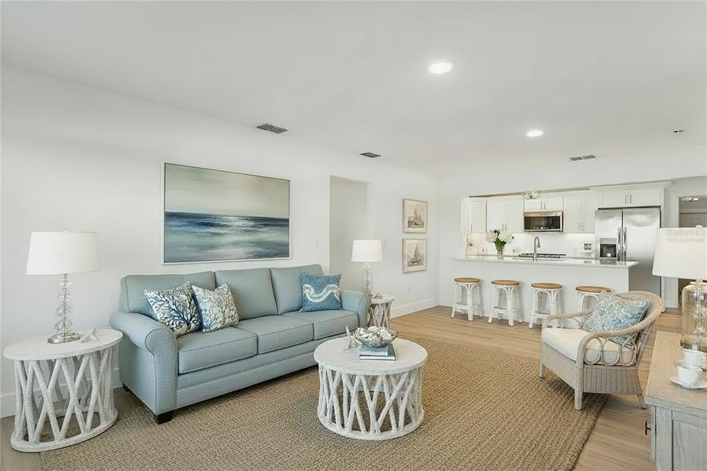 A living room with a blue sofa, white coffee table, and an open kitchen area — 5531 MANATEE POINT DRIVE, NEW PORT RICHEY, FL