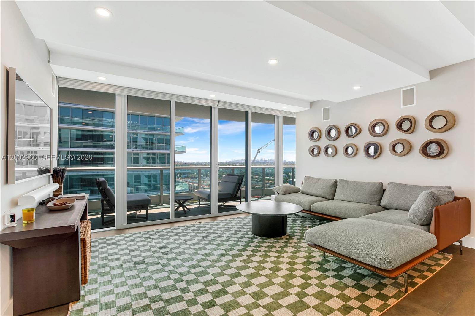 A modern living room features a checkered rug, a gray sectional, and floor-to-ceiling windows — 9401 Collins Ave # 1004, Surfside FL 33154, SURFSIDE, FL