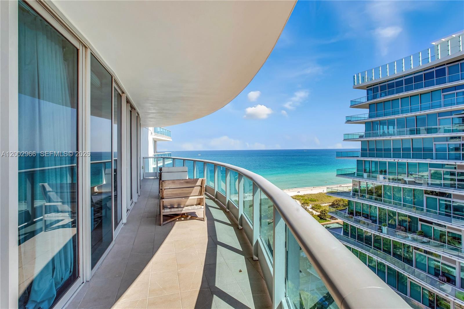 A curved balcony overlooks the ocean and a neighboring glass-fronted high-rise building — 9401 Collins Ave # 1004, Surfside FL 33154, SURFSIDE, FL