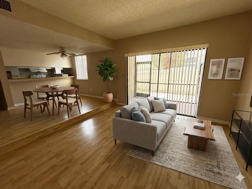 A living room with hardwood floors and a dining area on a raised platform — 1412 OAK PLACE UNIT J, APOPKA, FL