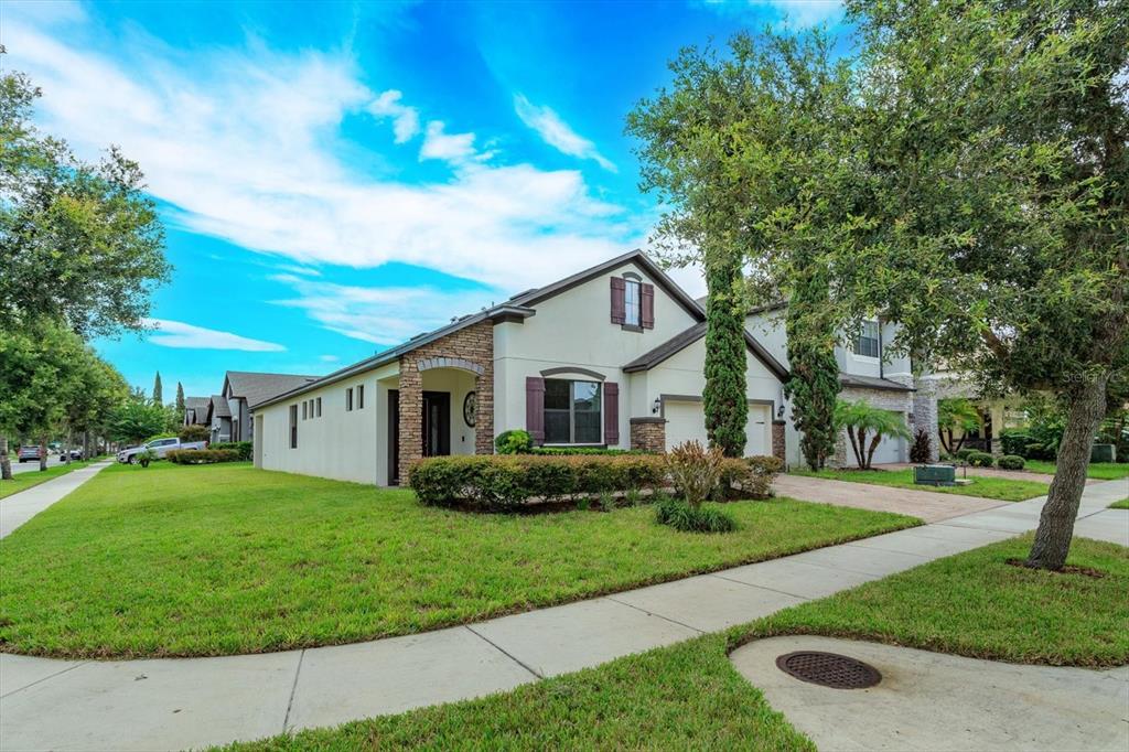 A two-story suburban house with a stone facade, a green lawn, and a paved driveway — 5106 APPENINE LOOP W, ST CLOUD, FL