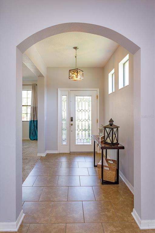An arched entryway leads to a front door with glass panels and a hanging light fixture — 5106 APPENINE LOOP W, ST CLOUD, FL