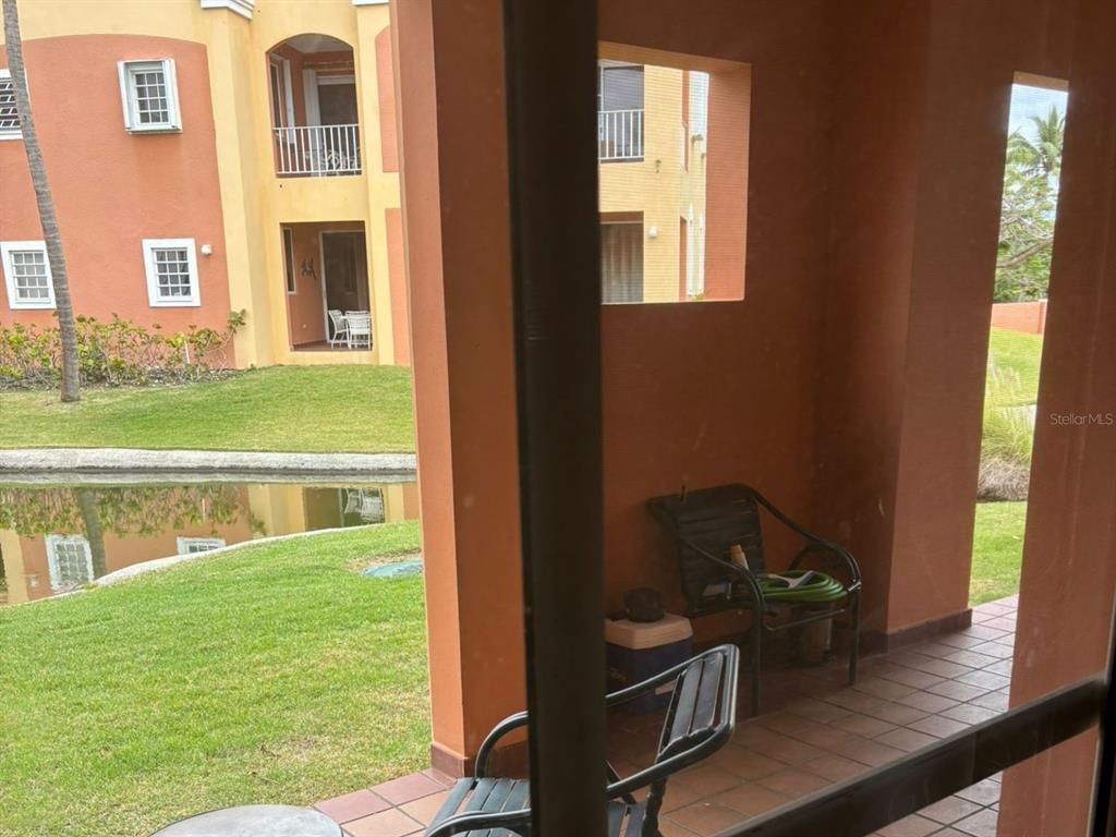 A covered patio overlooks a grassy lawn and a small pond near an apartment building — 150 SE CANDELERO DRIVE DRIVE UNIT 712, HUMACAO, PR