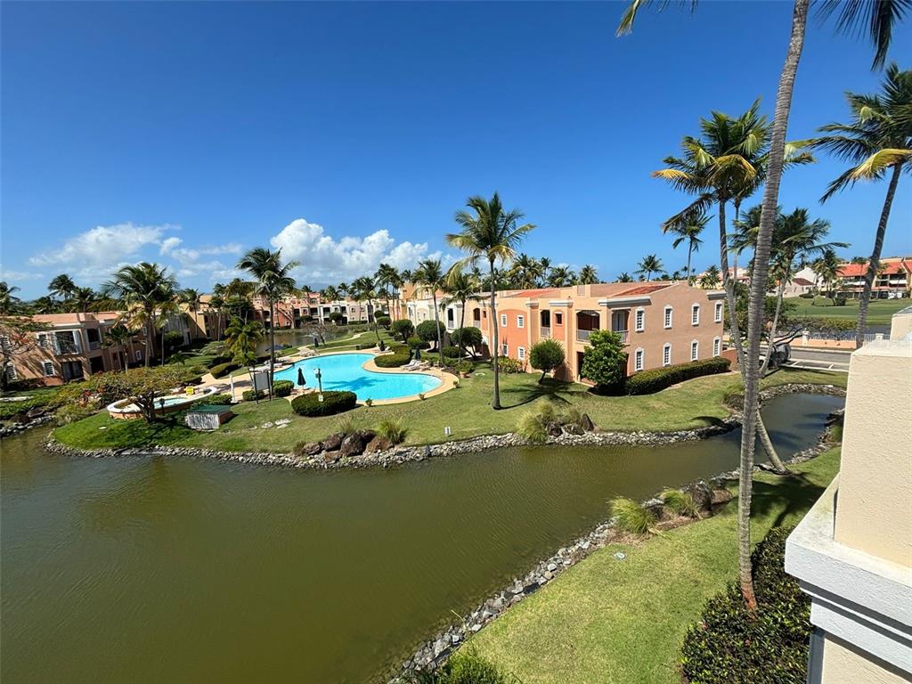 A view of a resort-style complex with a swimming pool, pond, and palm trees — 150 SE CANDELERO DRIVE DRIVE UNIT 712, HUMACAO, PR