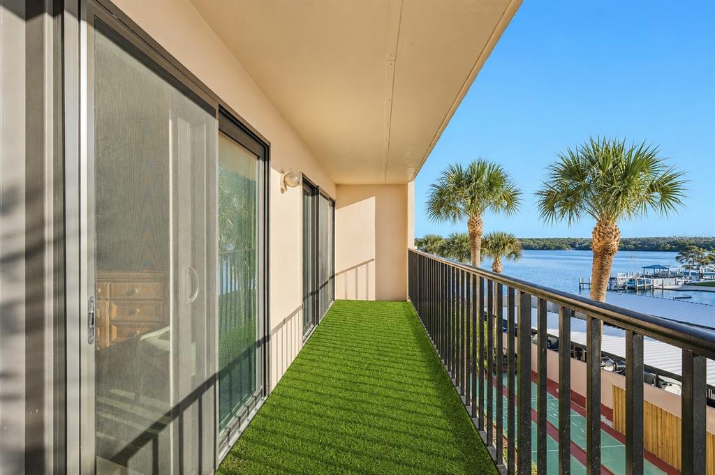 A balcony with artificial turf flooring, a black metal railing, and a view of water — 51 ISLAND WAY UNIT 311, CLEARWATER BEACH, FL