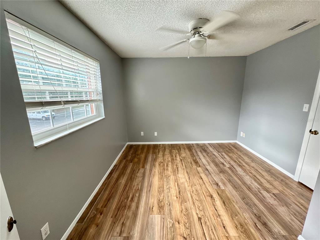 An empty bedroom features gray walls, wood-look flooring, a ceiling fan, and a large window — 3045 AARON BURR AVENUE UNIT 12D, WINTER PARK, FL