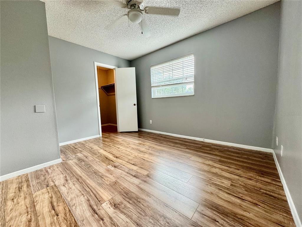 An empty bedroom features gray walls, wood-look flooring, a ceiling fan, and an open closet — 3045 AARON BURR AVENUE UNIT 12D, WINTER PARK, FL