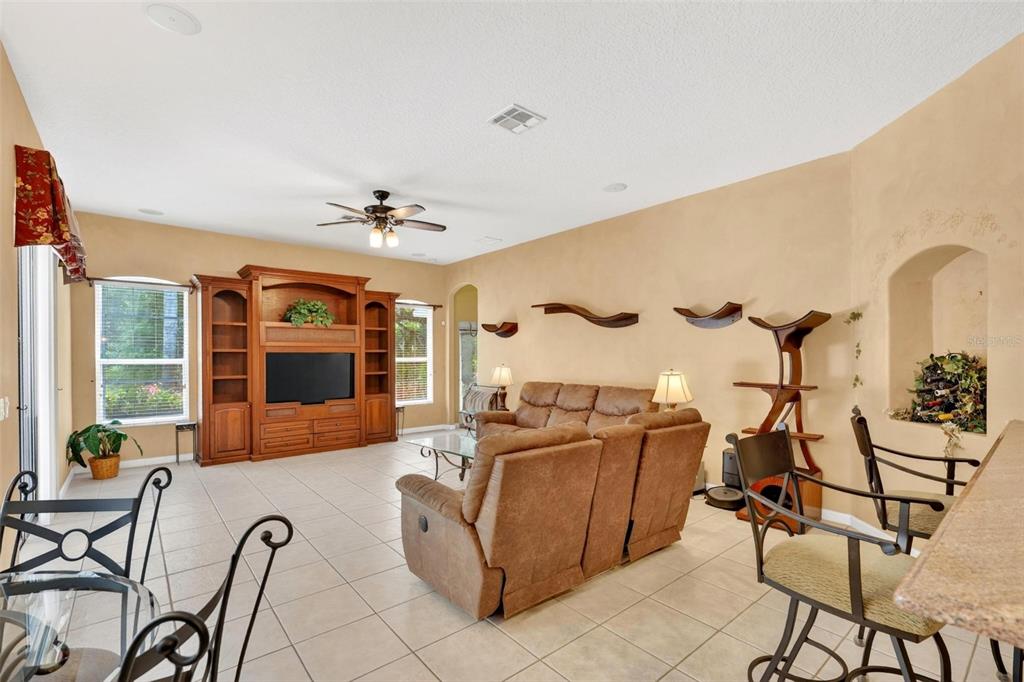 A living room features tan walls, tile flooring, a wooden entertainment center, and brown furniture — 4385 SEA ROCK COURT, APOPKA, FL
