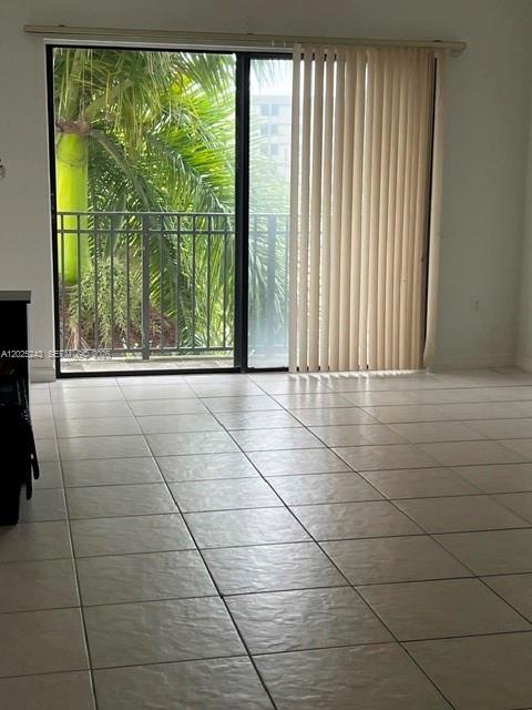 A room with light-colored tile flooring features a sliding glass door leading to a balcony — 650 Palm Ave # A2, Hialeah FL 33010, HIALEAH, FL