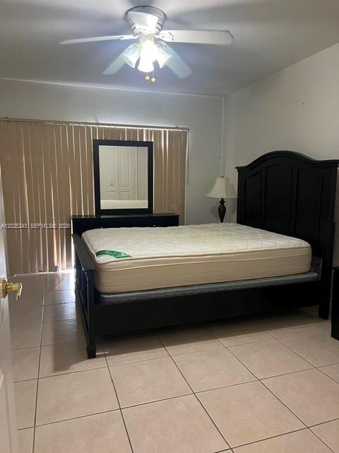 A bedroom features a dark wood bed frame, a matching dresser with a mirror, and tile flooring — 650 Palm Ave # A2, Hialeah FL 33010, HIALEAH, FL