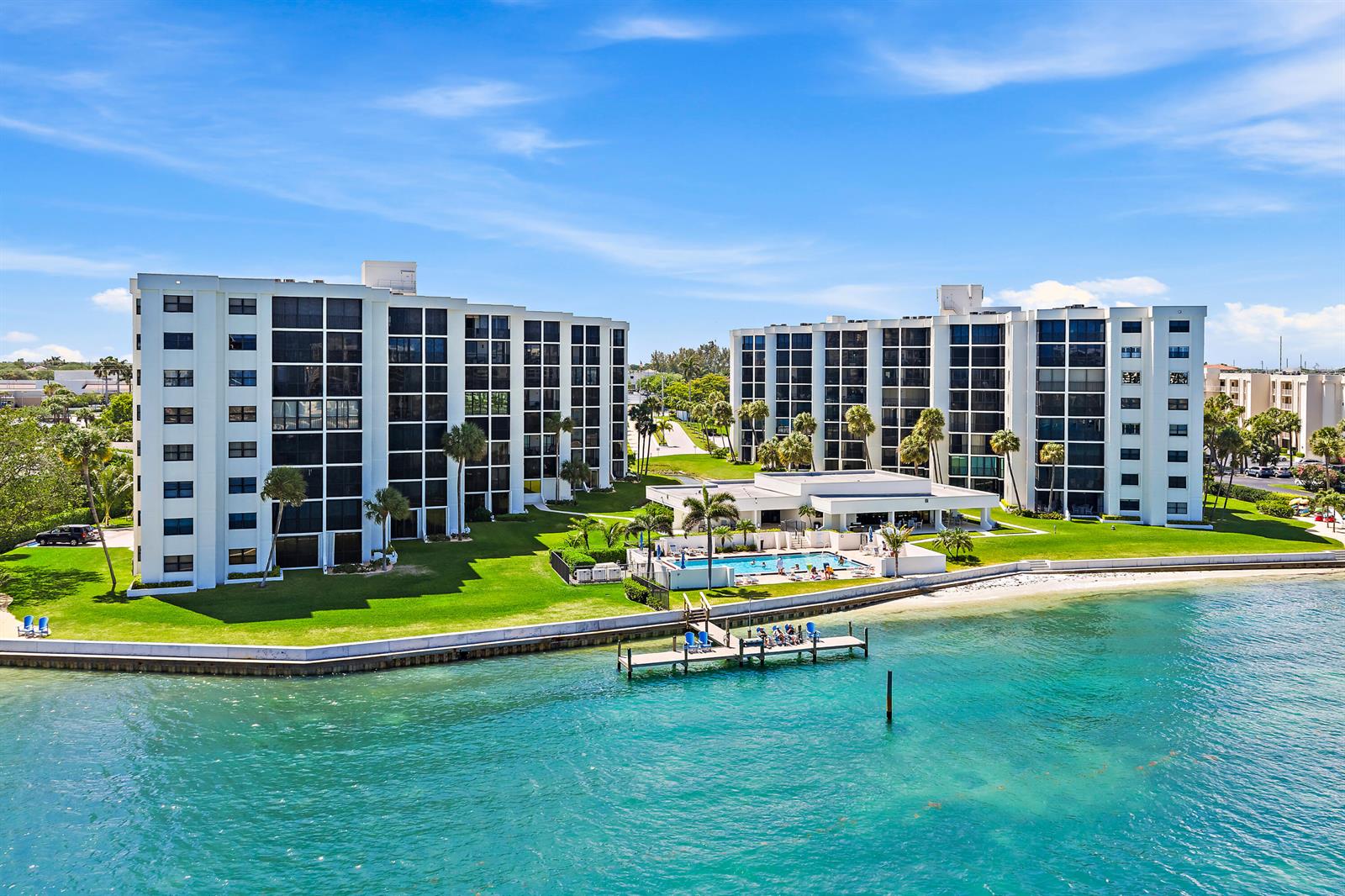 An aerial view shows two white apartment buildings with a pool and dock by water — 19800 Sandpointe Bay Drive # 305, Tequesta FL 33469, TEQUESTA, FL