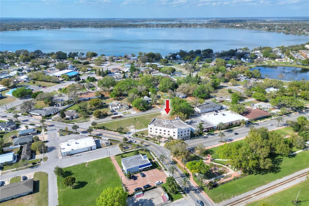 An aerial view shows a multi-story building with a red arrow pointing toward it — 206 PILAKLAKAHA AVENUE, AUBURNDALE, FL