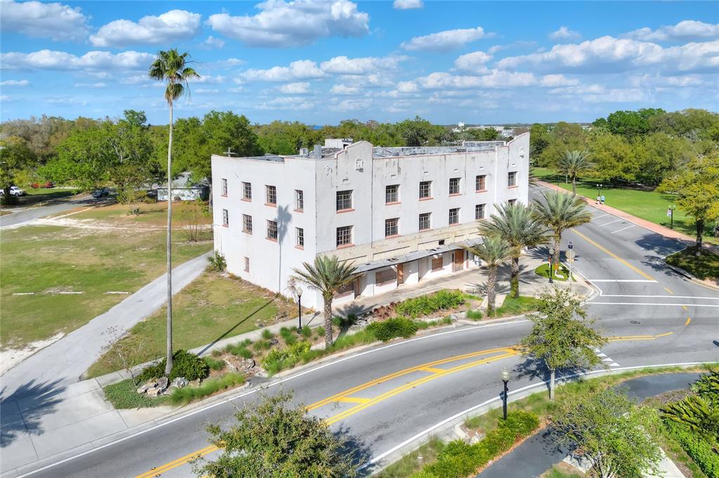 An aerial view of a three-story white commercial building situated near a curved road — 206 PILAKLAKAHA AVENUE, AUBURNDALE, FL