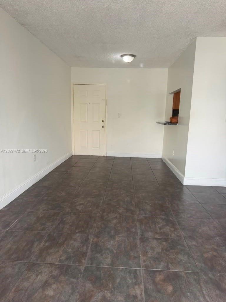 An empty room features white walls, dark tiled flooring, and a doorway — 8185 NW 7th St # 218, Miami FL 33126, MIAMI, FL