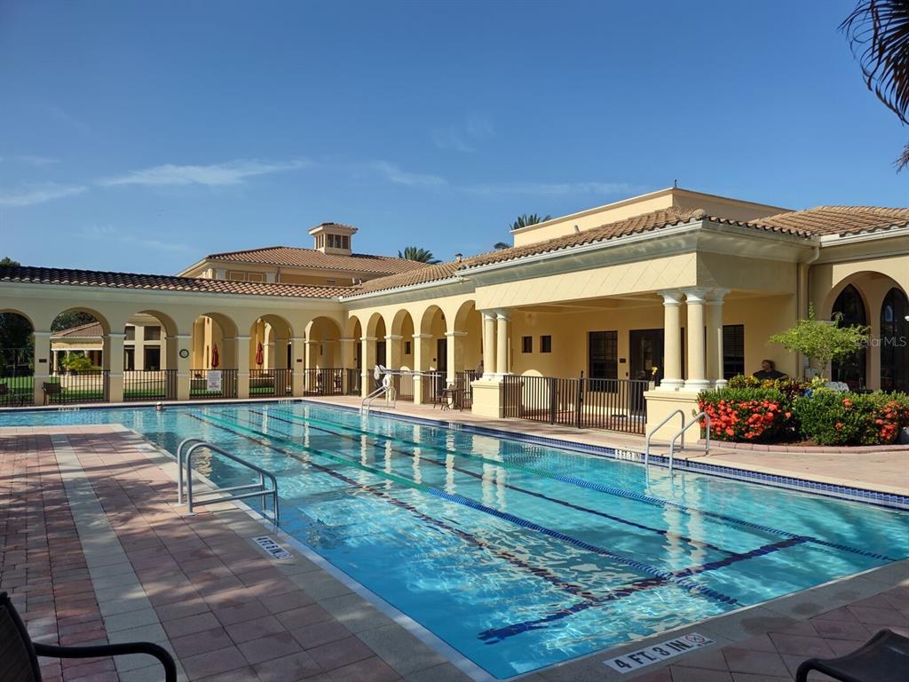 A rectangular swimming pool sits in front of a tan building with arched walkways — 209 MESTRE PLACE, NORTH VENICE, FL