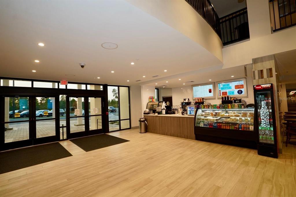 A bright lobby features a cafe counter, glass display cases, and large sliding glass doors — 15695 GROVE RESORT AVENUE UNIT 4303, WINTER GARDEN, FL
