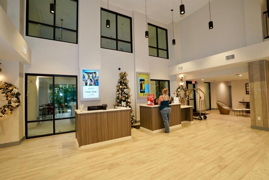 A modern hotel lobby features a reception desk, high ceilings, and large windows — 15695 GROVE RESORT AVENUE UNIT 4303, WINTER GARDEN, FL