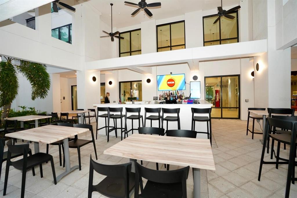 An outdoor bar area features tables, chairs, ceiling fans, and a television mounted on the wall — 15695 GROVE RESORT AVENUE UNIT 4303, WINTER GARDEN, FL