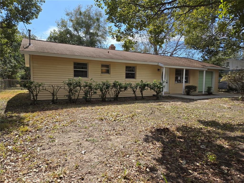 A single-story yellow house with a brown roof and a row of shrubs in front — 2204 SW 6TH STREET, OCALA, FL