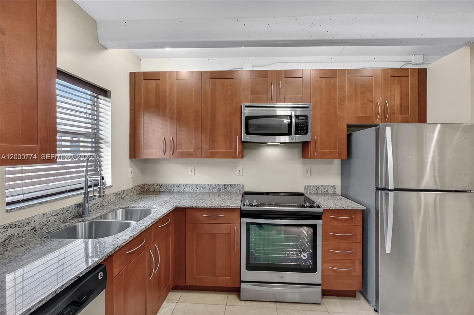 A kitchen features wood cabinets, granite countertops, stainless steel appliances, and a double sink — 1519 Drexel Ave, Miami Beach FL 33139, MIAMI BEACH, FL