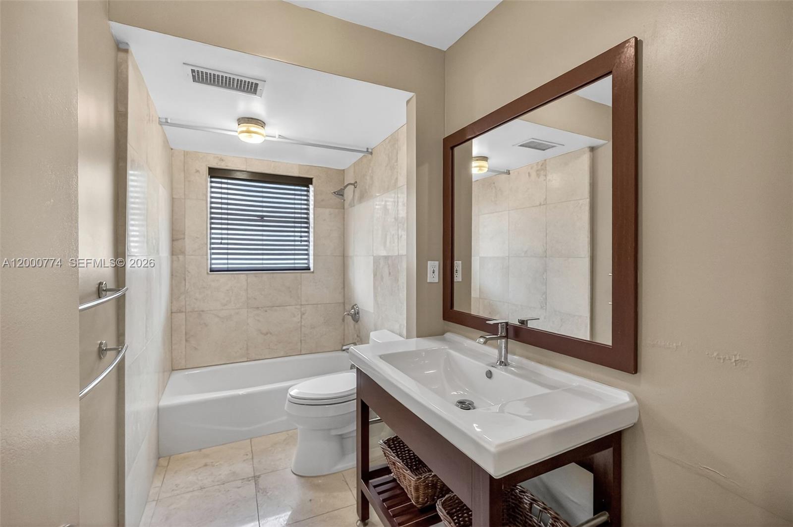 A bathroom features a vanity with a white sink, a toilet, and a tiled tub-shower — 1519 Drexel Ave, Miami Beach FL 33139, MIAMI BEACH, FL