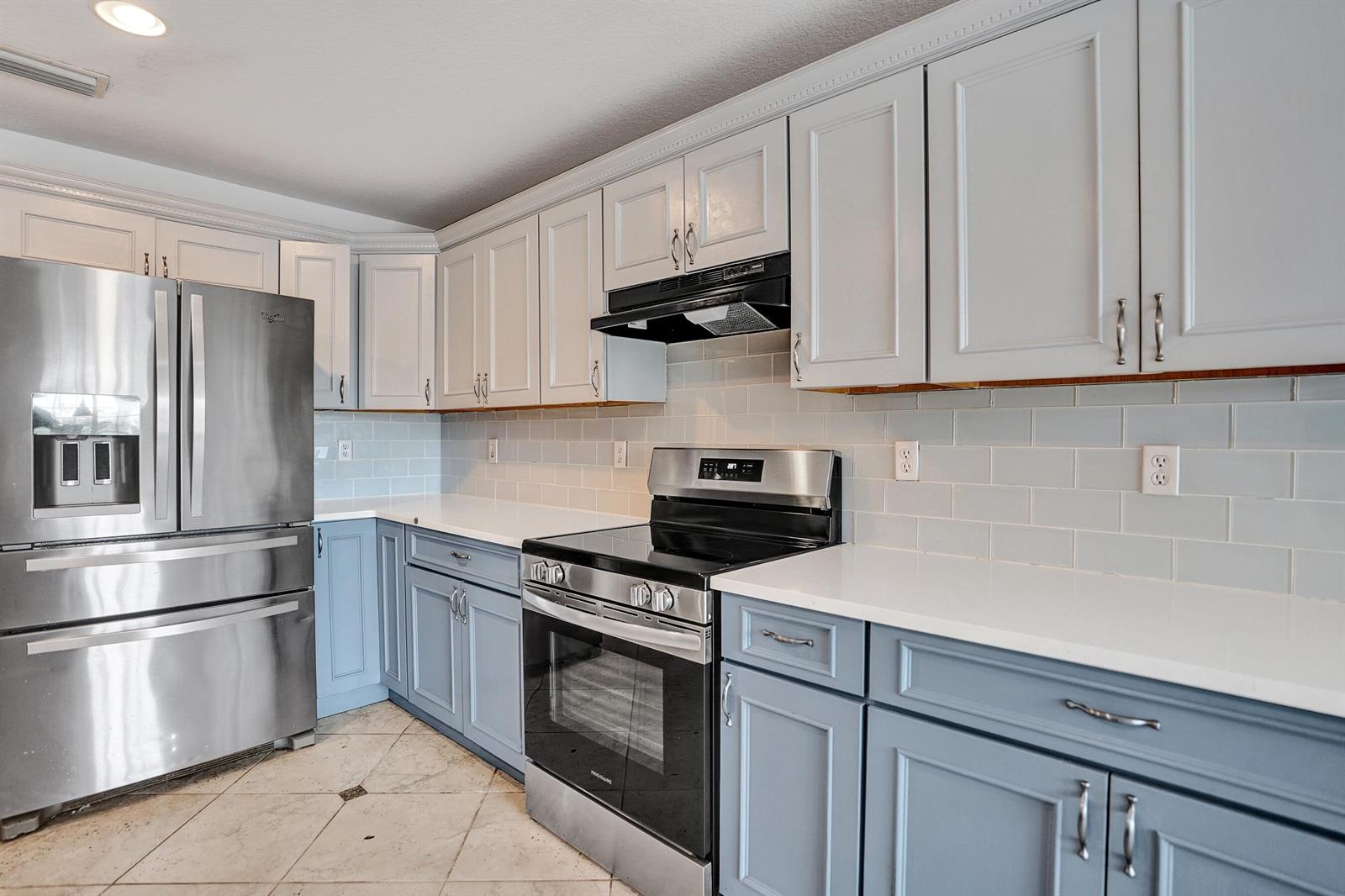 A kitchen features light blue lower cabinets, white upper cabinets, stainless steel appliances, and countertops — 9352 Cascade Court, Boynton Beach FL 33437, BOYNTON BEACH, FL