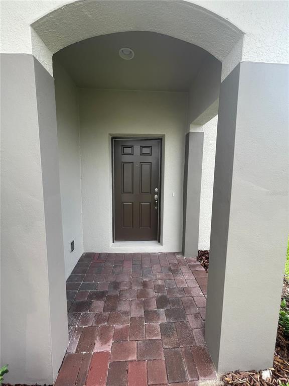 A covered entryway features a brown front door and red brick pavers — 2007 HANDSOME HILL LANE, DAVENPORT, FL