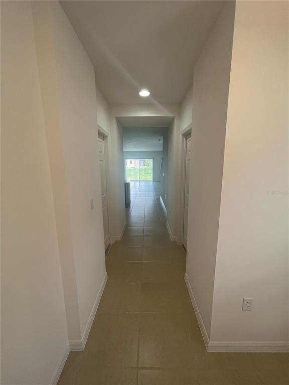 A tiled hallway leads from a foreground area toward a bright, open living space — 2007 HANDSOME HILL LANE, DAVENPORT, FL