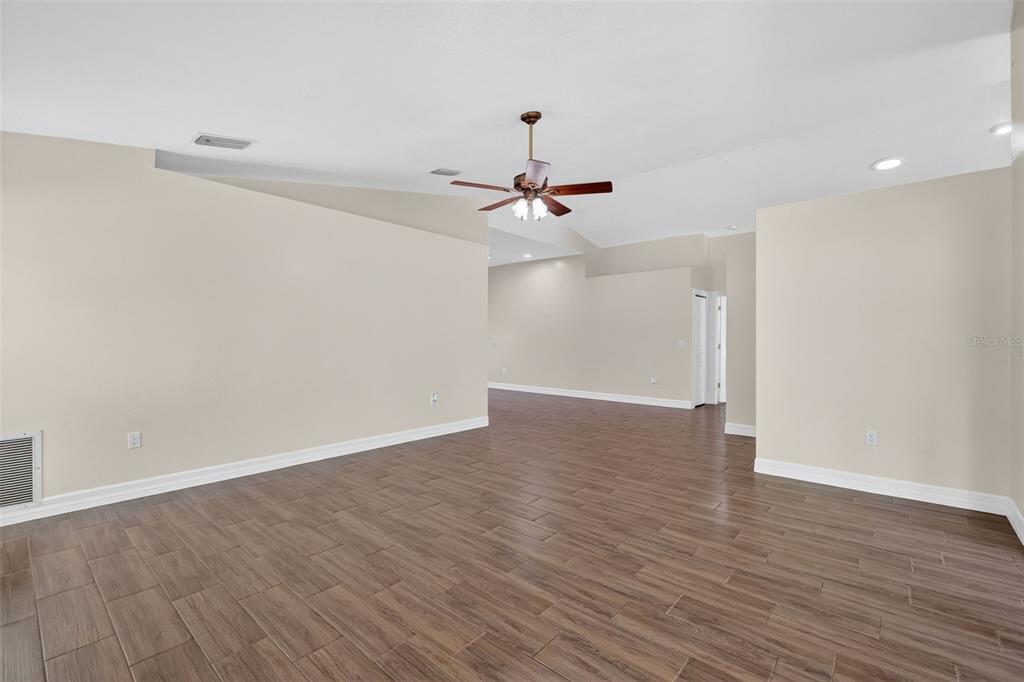 An empty room features wood-look tile flooring, beige walls, and a ceiling fan — 11637 LAKE DRIVE, LEESBURG, FL
