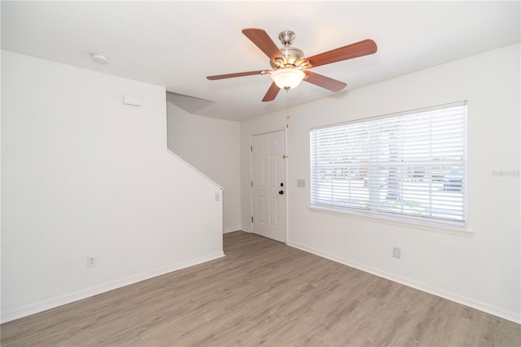 An empty room with white walls, wood-look flooring, a ceiling fan, and a front door — 344 CERVANTES DRIVE, KISSIMMEE, FL